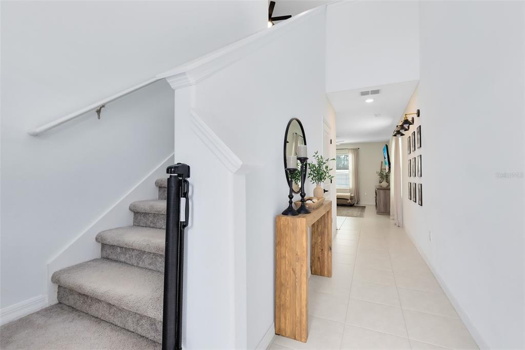 A carpeted staircase with a safety gate sits beside a hallway with a wooden console — 1791 YELLOW TRAIL, LAKELAND, FL