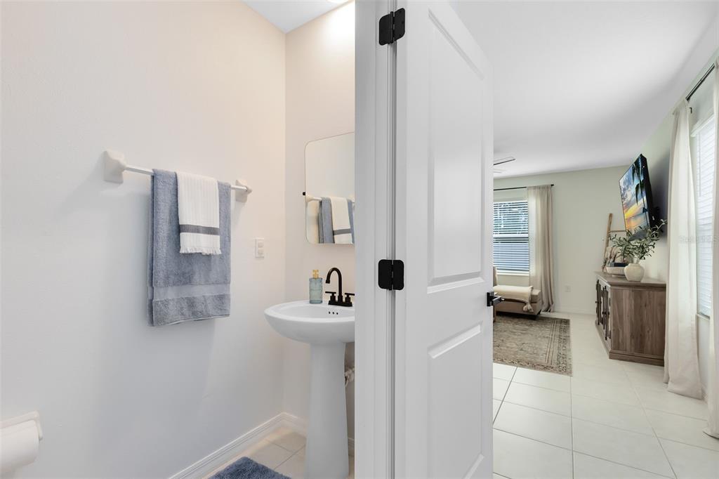 A small powder room with a pedestal sink and towel rack opens into a living area — 1791 YELLOW TRAIL, LAKELAND, FL