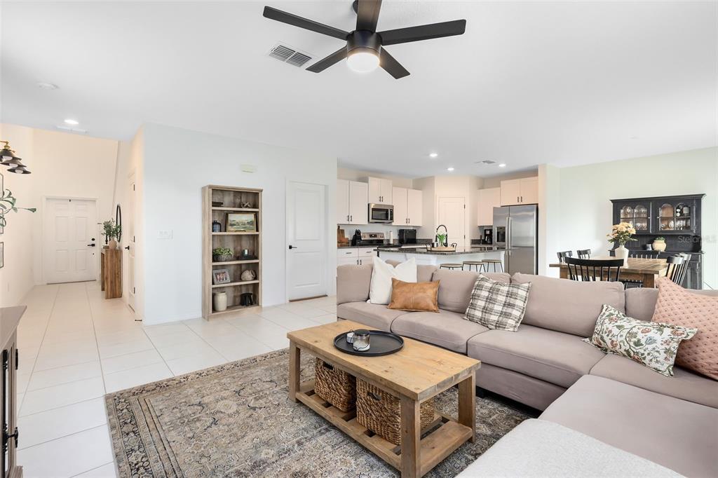 An open-concept living room with a sectional sofa, coffee table, and kitchen in the background — 1791 YELLOW TRAIL, LAKELAND, FL