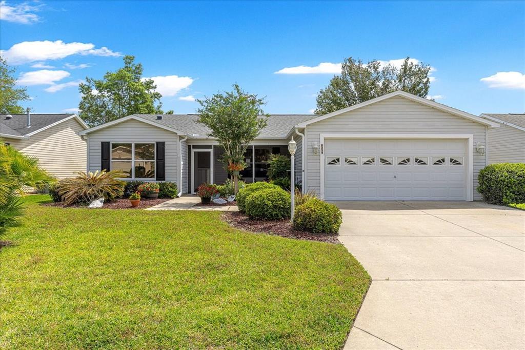 A single-story house with light gray siding, a two-car garage, and a front lawn — 8354 SE 177TH BARTRAM LOOP, THE VILLAGES, FL