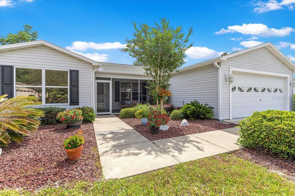 A single-story house with light gray siding, a two-car garage, and a landscaped front yard — 8354 SE 177TH BARTRAM LOOP, THE VILLAGES, FL