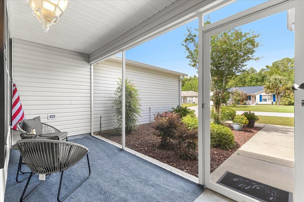 A screened-in porch with two chairs, blue carpeting, and a view of a suburban street — 8354 SE 177TH BARTRAM LOOP, THE VILLAGES, FL