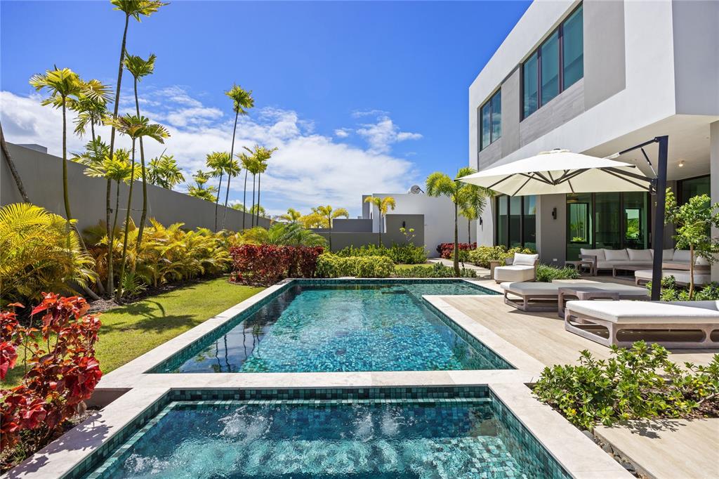 A modern house with a swimming pool, hot tub, and patio furniture in a landscaped yard — 39 THE ISLES, DORADO, PR