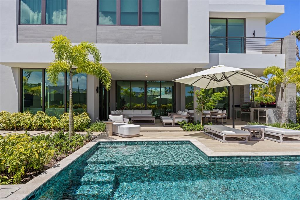 A modern house exterior features a tiled swimming pool, patio furniture, and a large umbrella — 39 THE ISLES, DORADO, PR