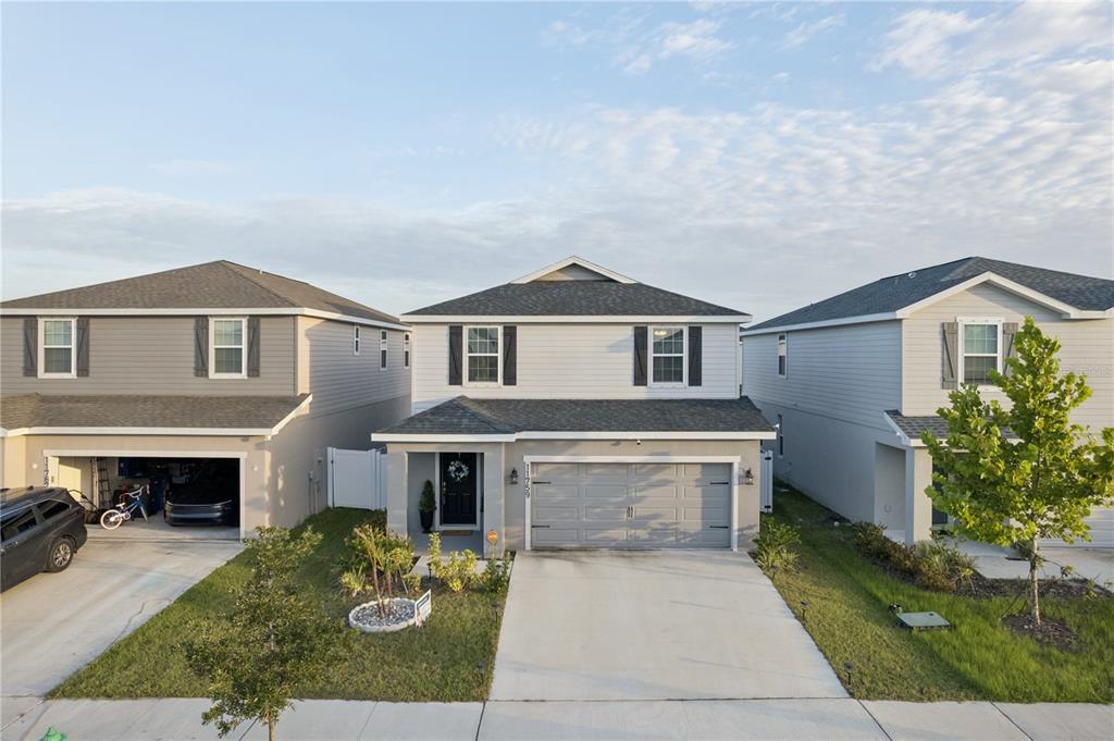 A two-story suburban house with a gray garage, light siding, and a concrete driveway — 11759 SABAL SCRUB COURT, RIVERVIEW, FL