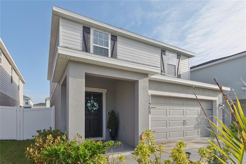 A two-story house with light gray siding, a stucco entryway, and a two-car garage — 11759 SABAL SCRUB COURT, RIVERVIEW, FL