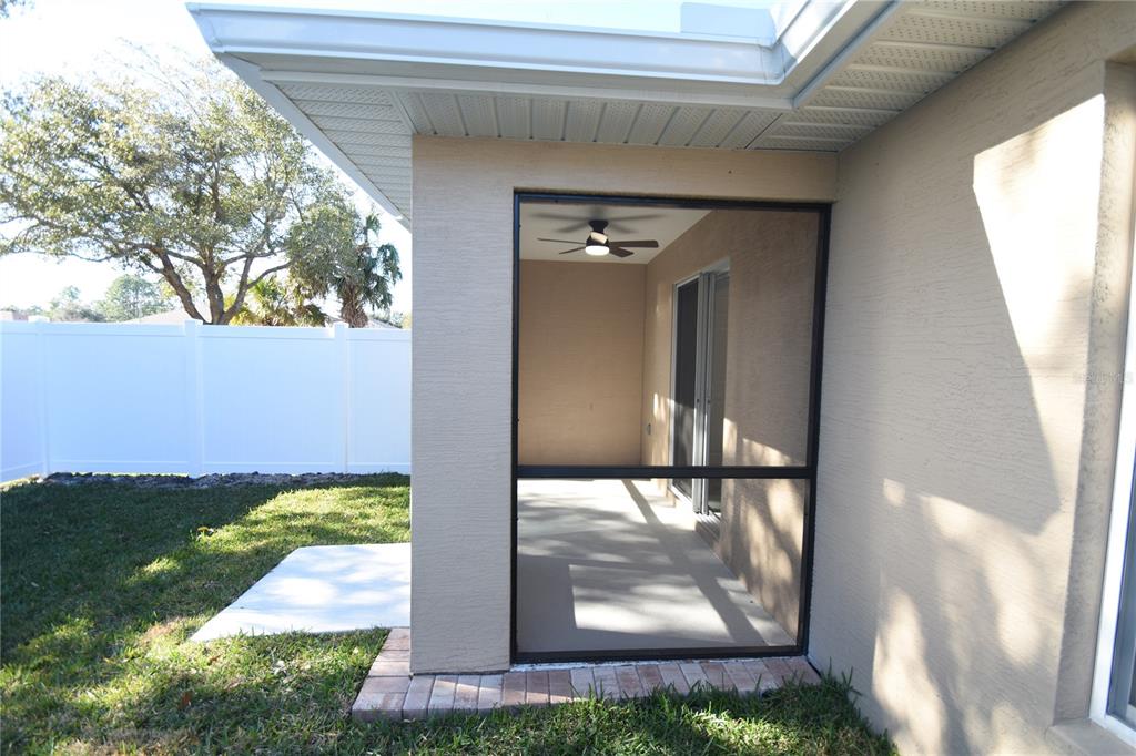 A screened-in patio with a ceiling fan sits adjacent to a white vinyl fence — 11 BUTTONWOOD LANE UNIT A, PALM COAST, FL