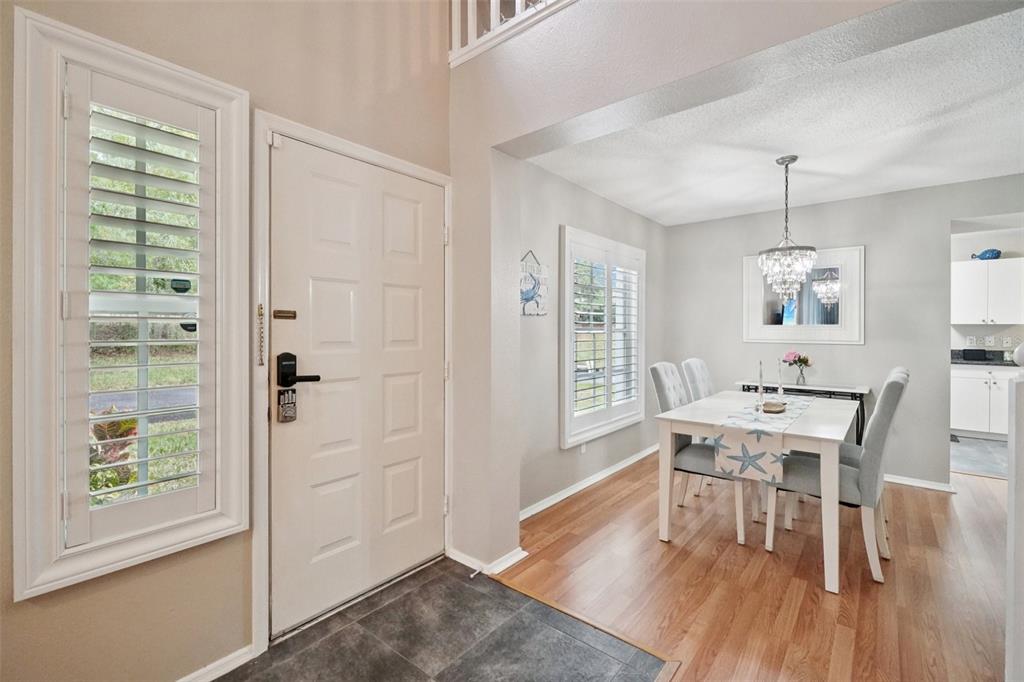 An entryway with tile flooring leads to a dining room featuring wood floors and shutters — 2243 ANDOVER CIRCLE, PALM HARBOR, FL