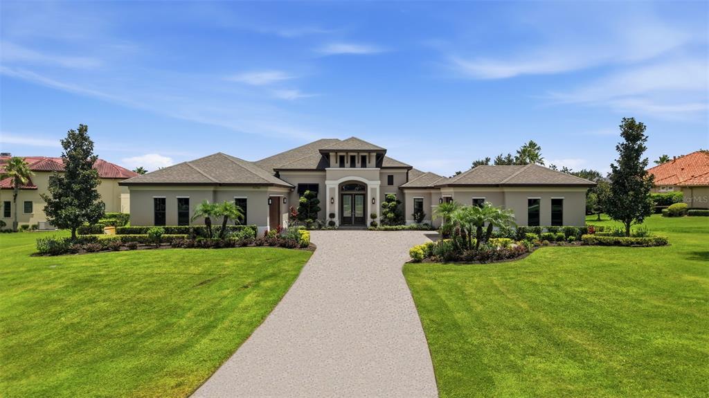A single-story house with a beige exterior, a gray roof, and a long concrete driveway — 10741 OSPREY LANDING WAY, THONOTOSASSA, FL