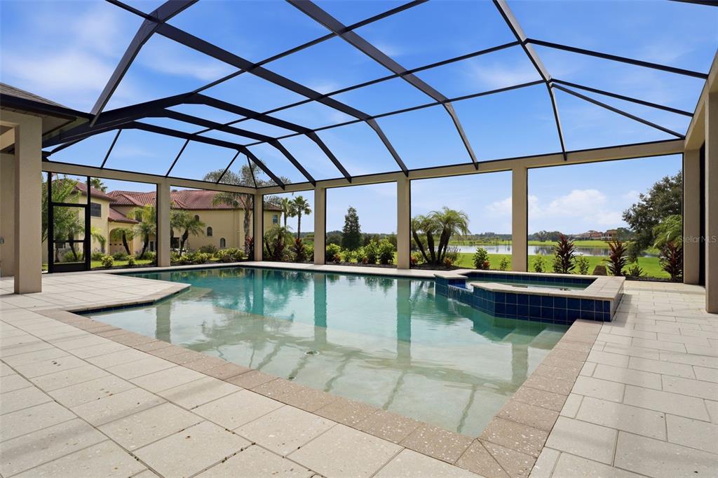 A screened-in swimming pool and spa overlook a grassy lawn and a distant lake — 10741 OSPREY LANDING WAY, THONOTOSASSA, FL