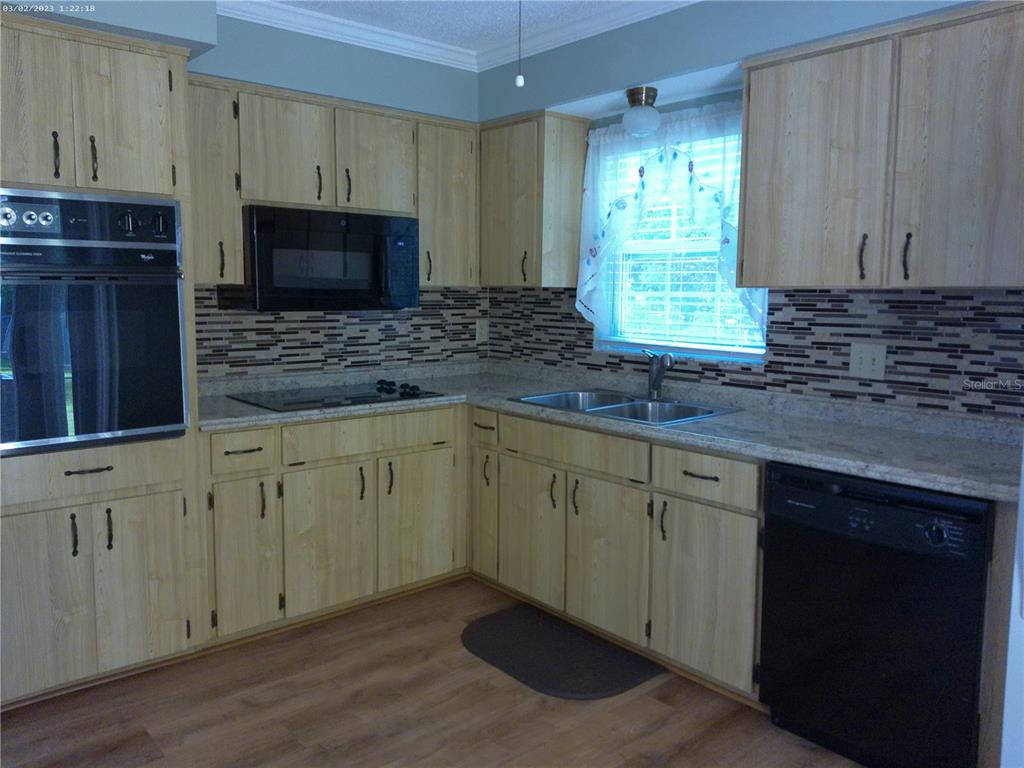 A kitchen features light wood cabinets, a black microwave, a wall oven, and a dishwasher — 6118 WILDS DRIVE UNIT 0, NEW PORT RICHEY, FL