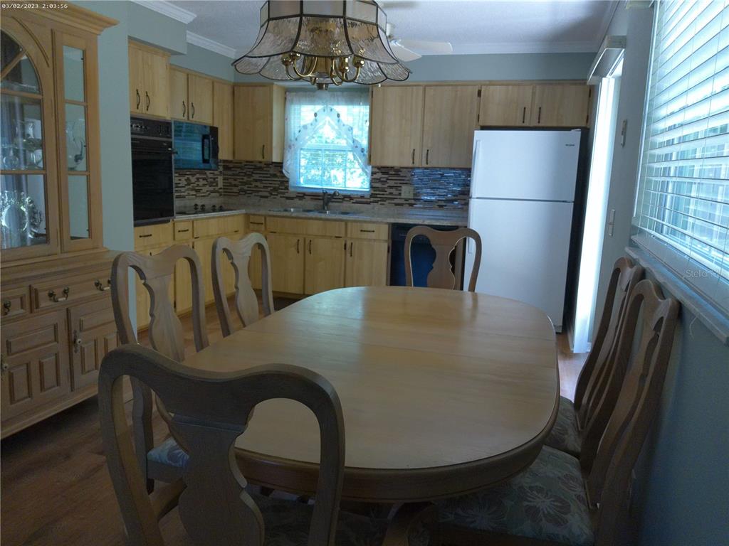 A dining area with a wooden table and chairs sits adjacent to a kitchen — 6118 WILDS DRIVE UNIT 0, NEW PORT RICHEY, FL
