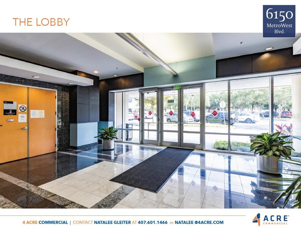 The lobby features a polished tile floor, glass entrance doors, and a large black rug — 6150 METROWEST BOULEVARD UNIT 302, ORLANDO, FL