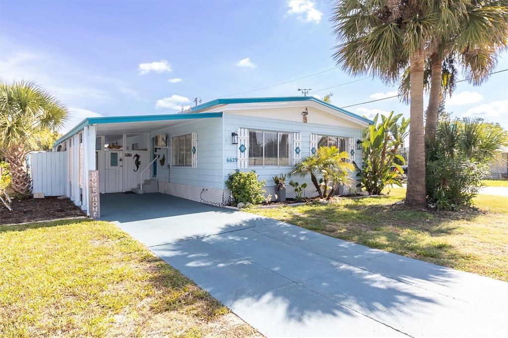 A light blue mobile home features a covered carport and a paved driveway — 6629 TOWER DRIVE, HUDSON, FL