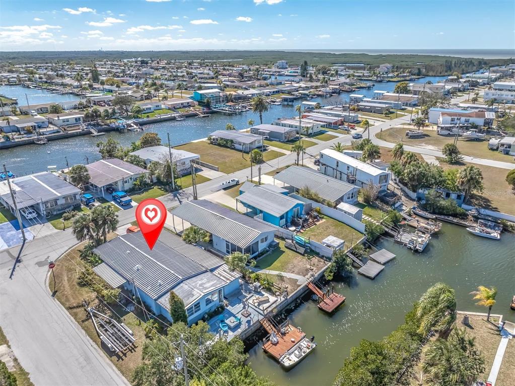 An aerial view shows a waterfront house with a metal roof and private boat dock — 6629 TOWER DRIVE, HUDSON, FL