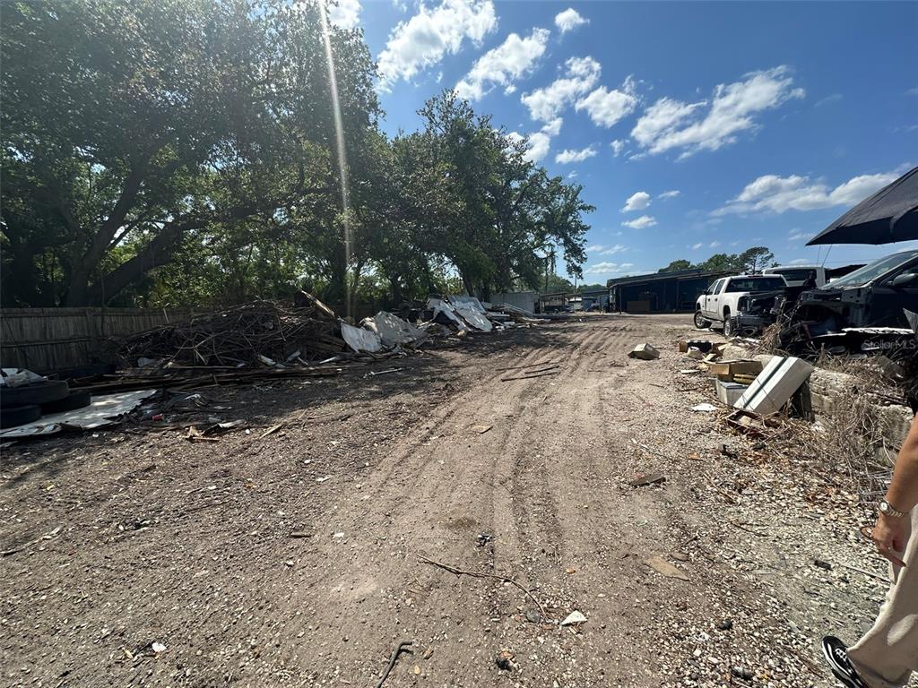 An outdoor lot features a dirt path, scattered debris, and a line of trees — 8020 S 78TH STREET, RIVERVIEW, FL