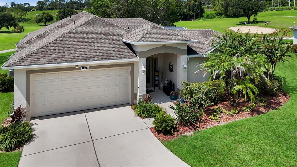 A single-story house with a two-car garage sits on a golf course lot — 1940 FARMINGTON COURT, CLERMONT, FL
