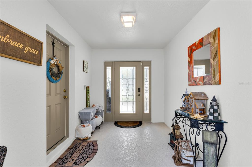 An entryway features a front door with glass panels, a side door, and a console table — 1940 FARMINGTON COURT, CLERMONT, FL