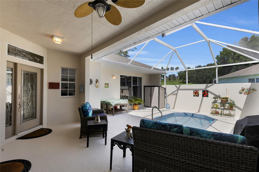 A covered patio features a small pool, wicker furniture, and a screened-in enclosure — 1940 FARMINGTON COURT, CLERMONT, FL