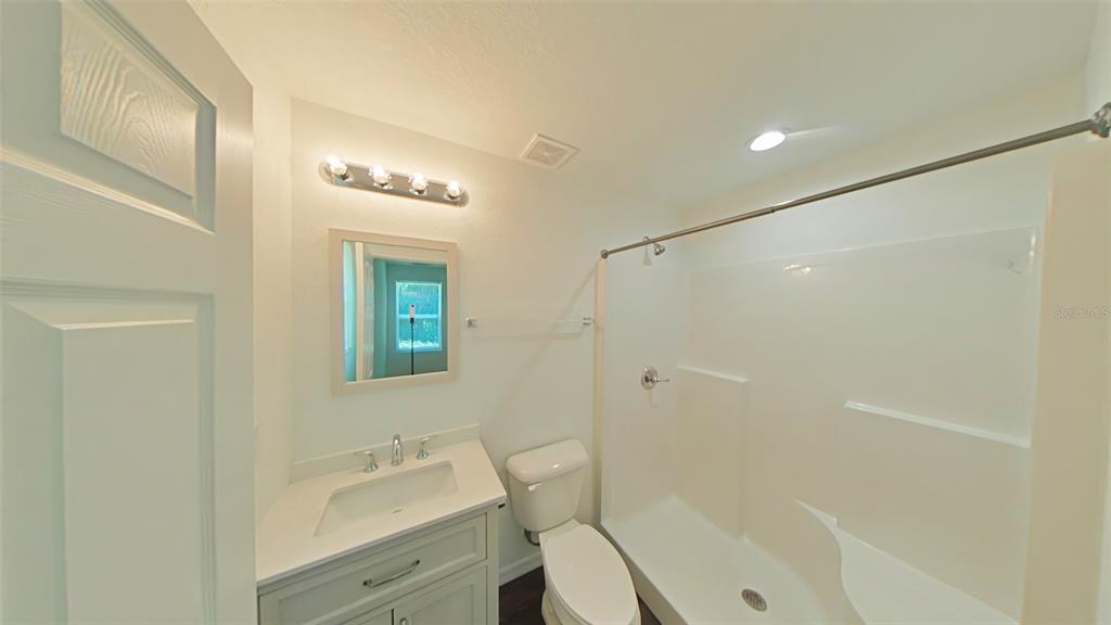A bathroom features a vanity with a white countertop, a toilet, and a shower-tub combo — 3780 SE 141ST LANE, SUMMERFIELD, FL