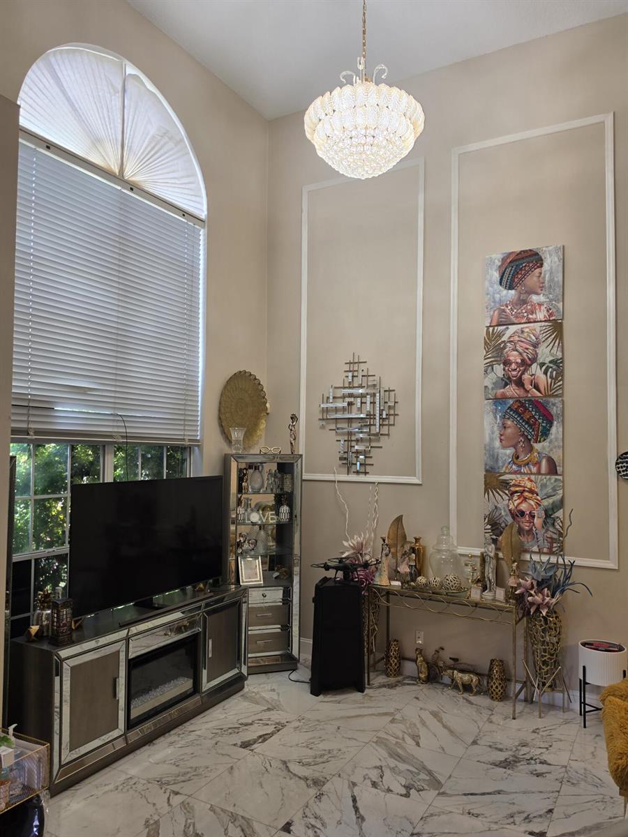 A living room features a tall arched window, mirrored furniture, marble flooring, and decorative wall art — 5351 NW 41st Way, Coconut Creek FL 33073, COCONUT CREEK, FL