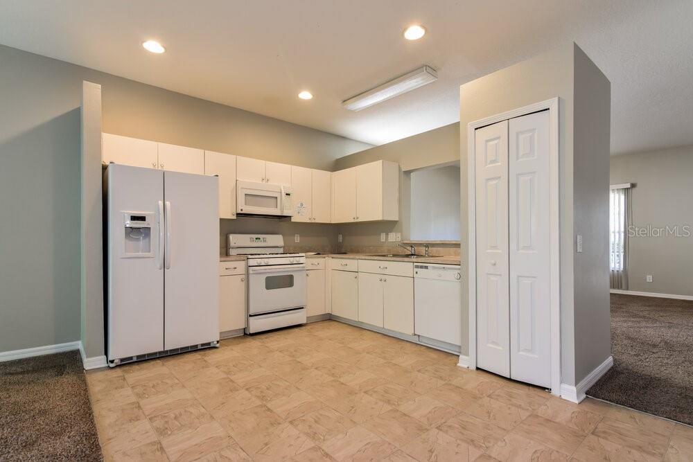 A kitchen with white cabinets, white appliances, and light-colored tile flooring — 15819 STAGS LEAP DRIVE, LUTZ, FL