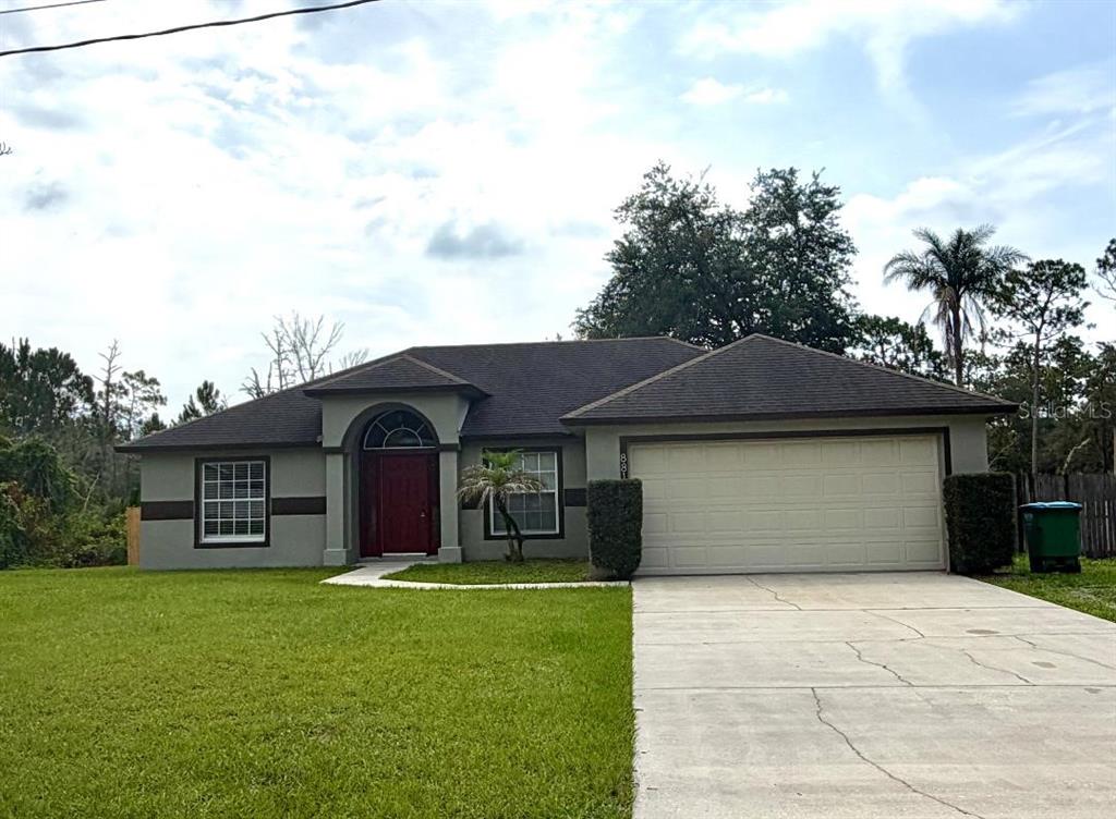A single-story house with a gray exterior, a red front door, and a two-car garage — 881 HANFORD DRIVE, DELTONA, FL