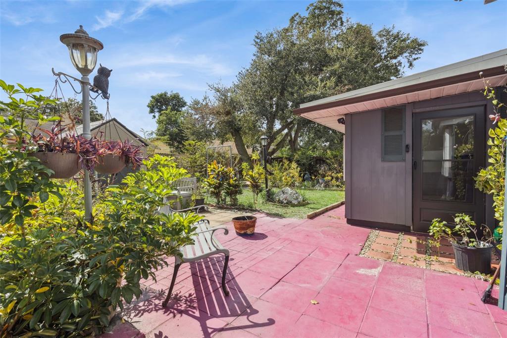 A red-tiled patio features a metal bench, hanging plants, and a view of the backyard — 3646 FALLING LEAF LANE, ORLANDO, FL