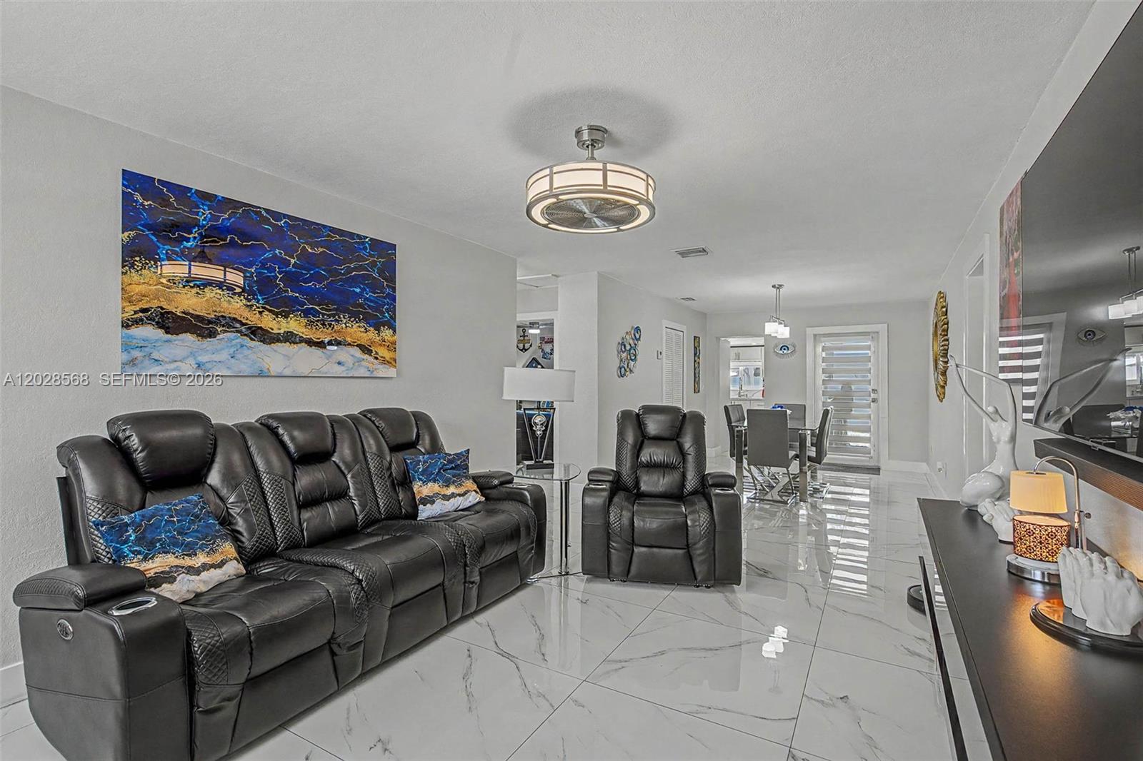 A living room features black leather furniture, white marble-look tile floors, and a ceiling fan — 10345 NW 35th Ct, Miami FL 33147, MIAMI, FL