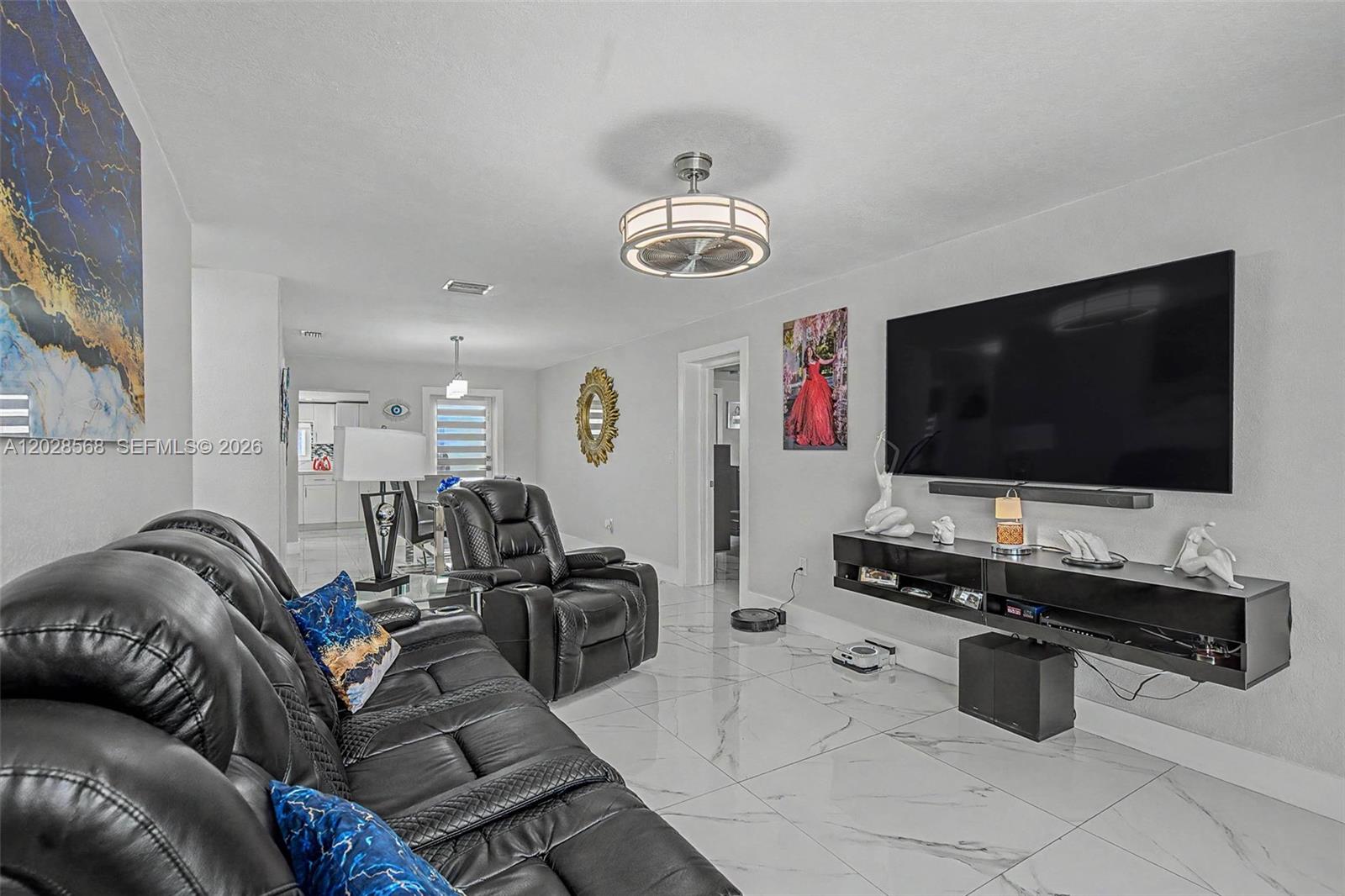 A living room features a large television, black leather furniture, and white marble-style flooring — 10345 NW 35th Ct, Miami FL 33147, MIAMI, FL