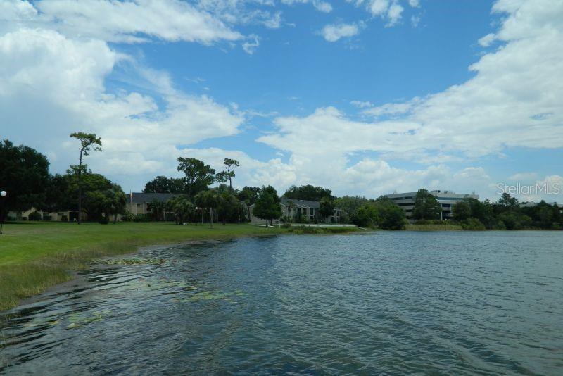 A view of a lake with grassy banks, trees, and apartment buildings in the distance — 922 LAKE DESTINY ROAD UNIT E, ALTAMONTE SPRINGS, FL