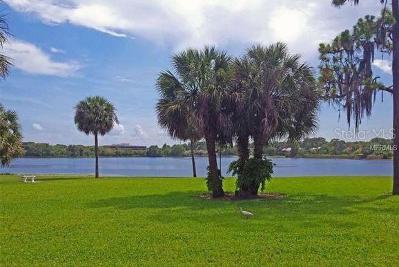A grassy lawn with palm trees and a bird overlooks a lake under a blue sky — 922 LAKE DESTINY ROAD UNIT E, ALTAMONTE SPRINGS, FL