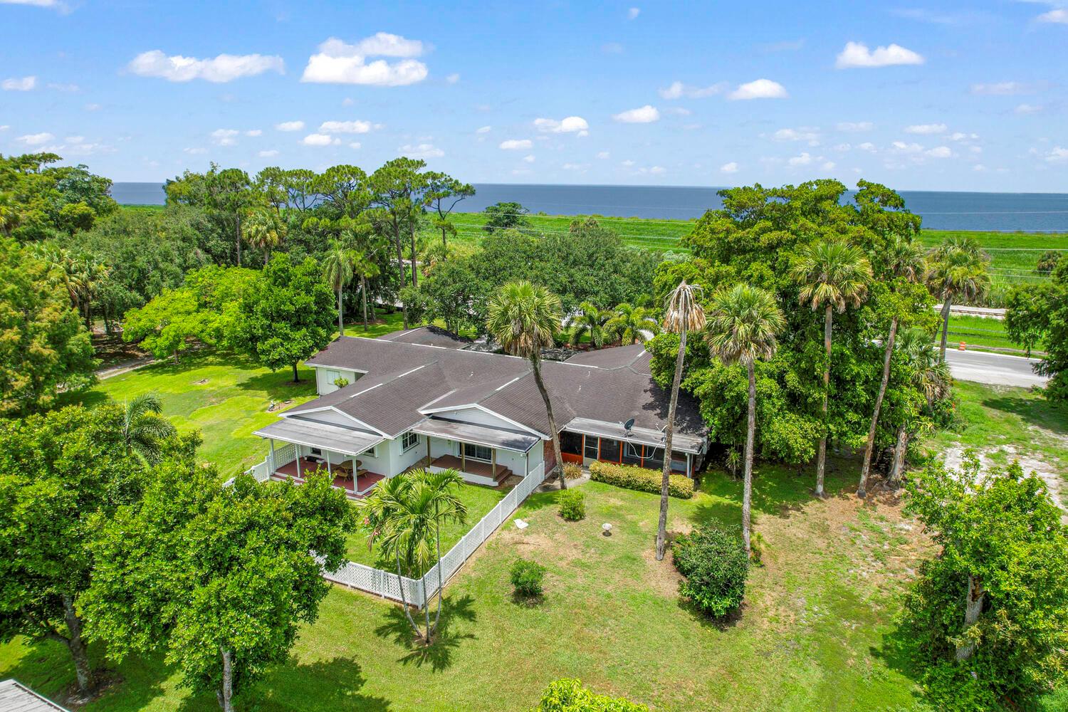 An aerial view of a single-story house with a dark roof surrounded by lush trees — 13348 Us Highway 441, Canal Point FL 33438, CANAL POINT, FL