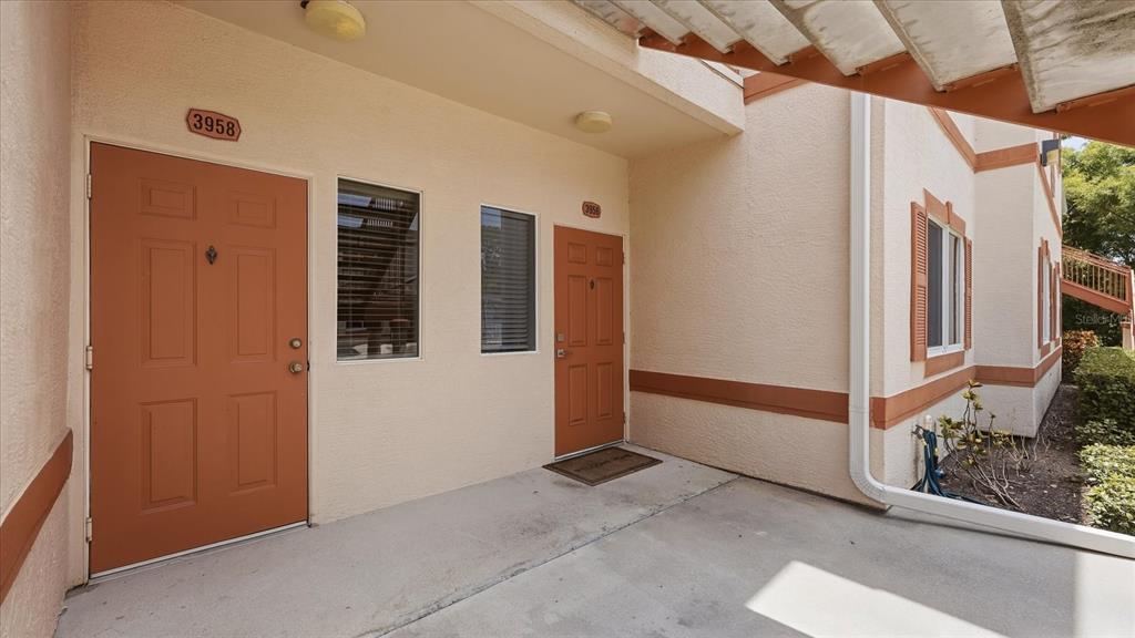 An exterior view shows two orange doors and a concrete walkway under a wooden pergola — 3958 MEDITERRANEA CIRCLE UNIT 411, SARASOTA, FL
