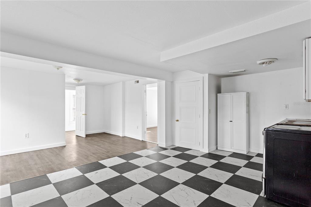 A room with a black and white checkered floor transitions into a wood-floored living area — 4103 N HOWARD AVENUE, TAMPA, FL