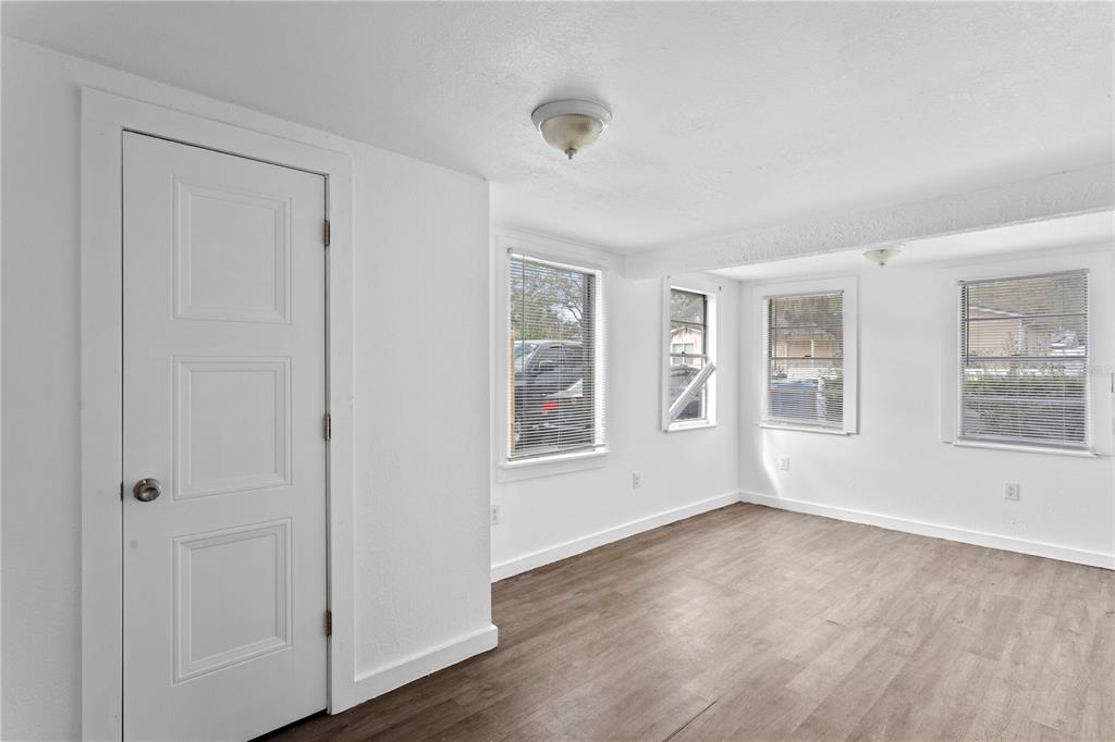 A bright room features white walls, wood-look flooring, a single door, and multiple windows — 4103 N HOWARD AVENUE, TAMPA, FL