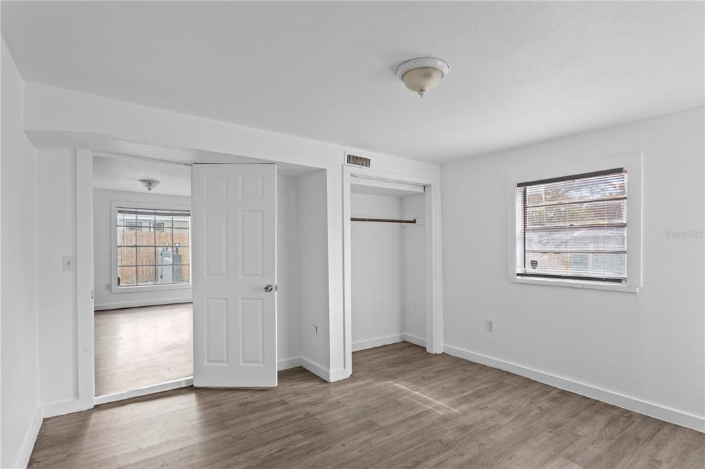 A bedroom with white walls, wood-look flooring, a closet, and a doorway to another room — 4103 N HOWARD AVENUE, TAMPA, FL