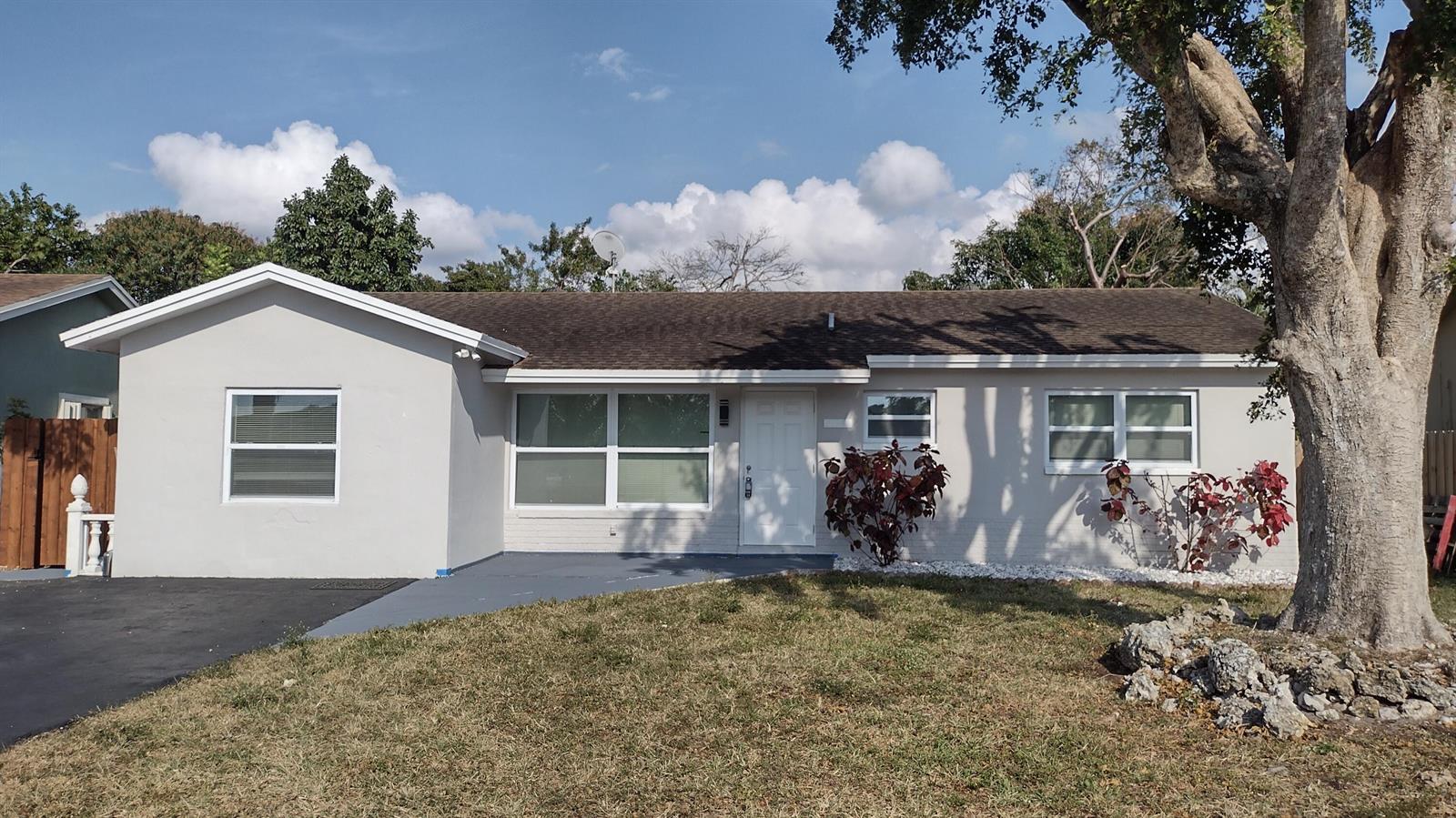 A single-story house with a gray exterior, a paved driveway, and a large front tree — 22682 Family Circle, Boca Raton FL 33428, BOCA RATON, FL