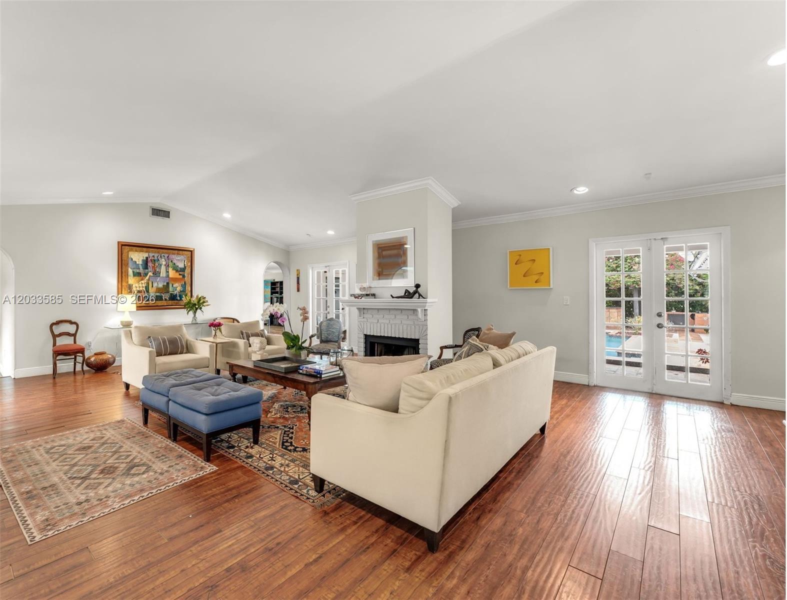 A living room features hardwood floors, a central fireplace, and French doors leading outdoors — 7603 SW 91st Ave, Miami FL 33173, MIAMI, FL