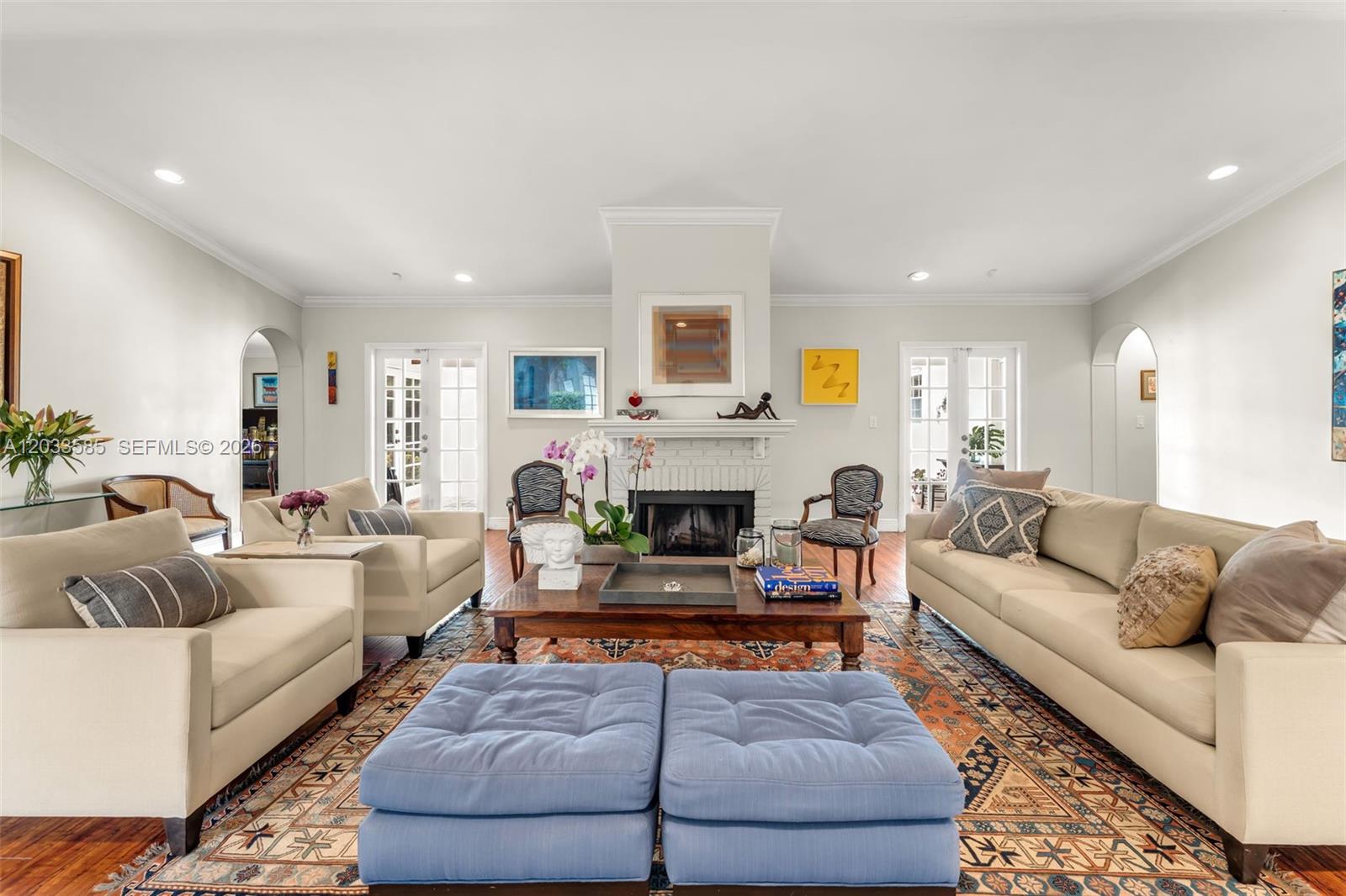 A living room features a central fireplace, beige sofas, blue ottomans, and a patterned rug — 7603 SW 91st Ave, Miami FL 33173, MIAMI, FL