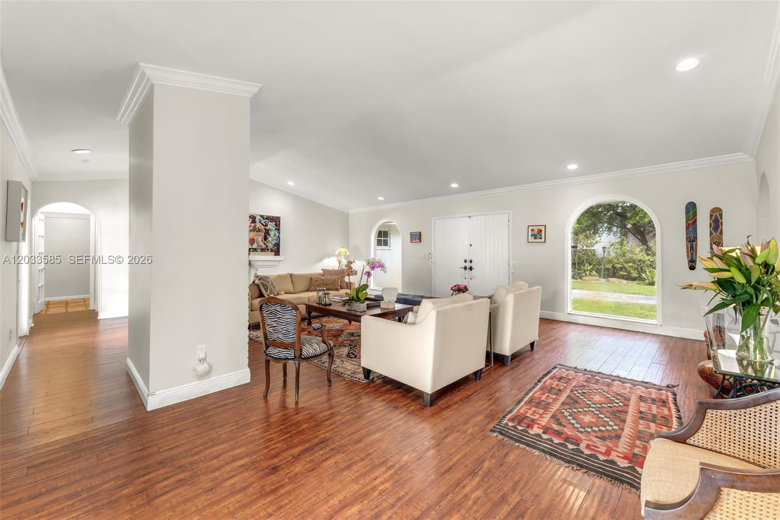 A living room features hardwood floors, white walls, arched windows, and a neutral furniture arrangement — 7603 SW 91st Ave, Miami FL 33173, MIAMI, FL