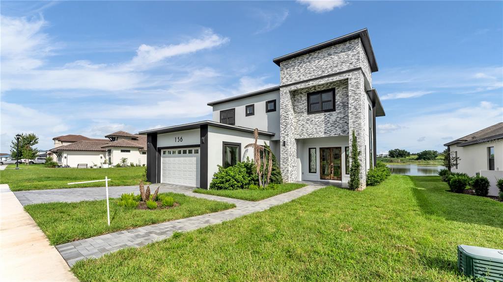 A two-story modern house with a stone facade, a garage, and a paved walkway — 156 CALADIUM AVENUE, LAKE ALFRED, FL
