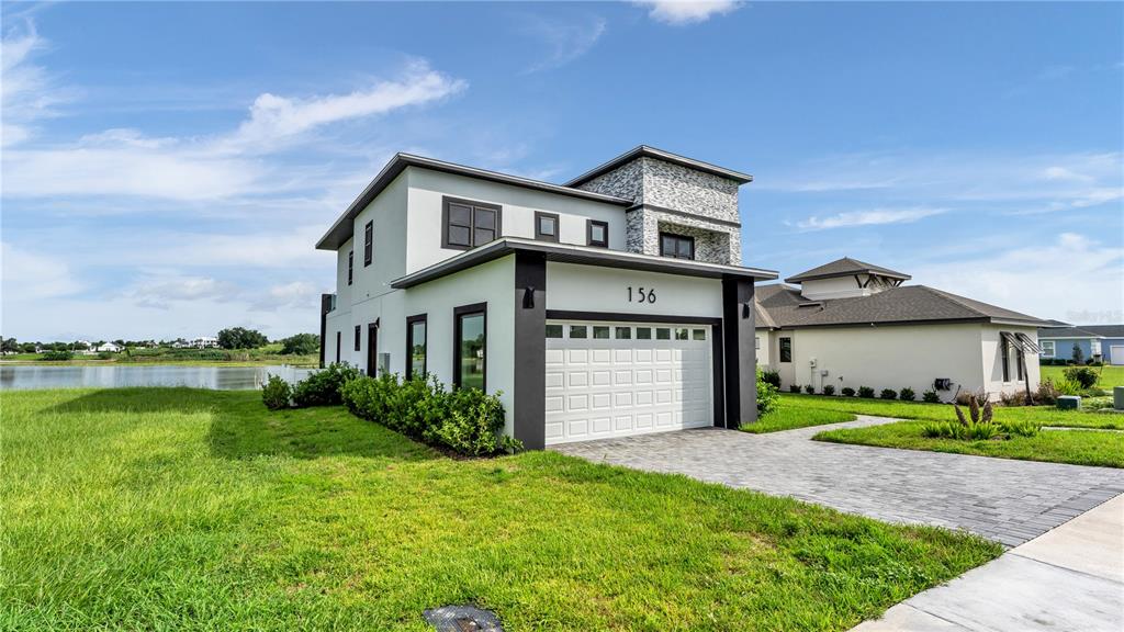 A two-story modern house with a white exterior, stone accents, and a two-car garage — 156 CALADIUM AVENUE, LAKE ALFRED, FL