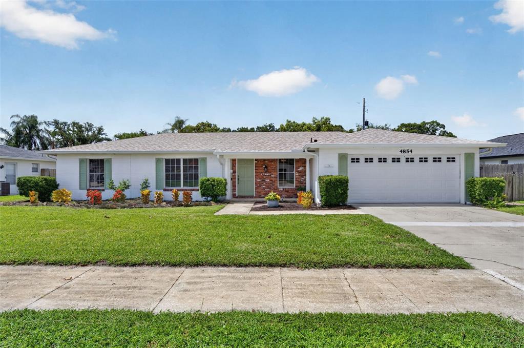 A single-story house with a white exterior, brick accents, and a two-car garage — 4854 RABAMA PLACE, ORLANDO, FL