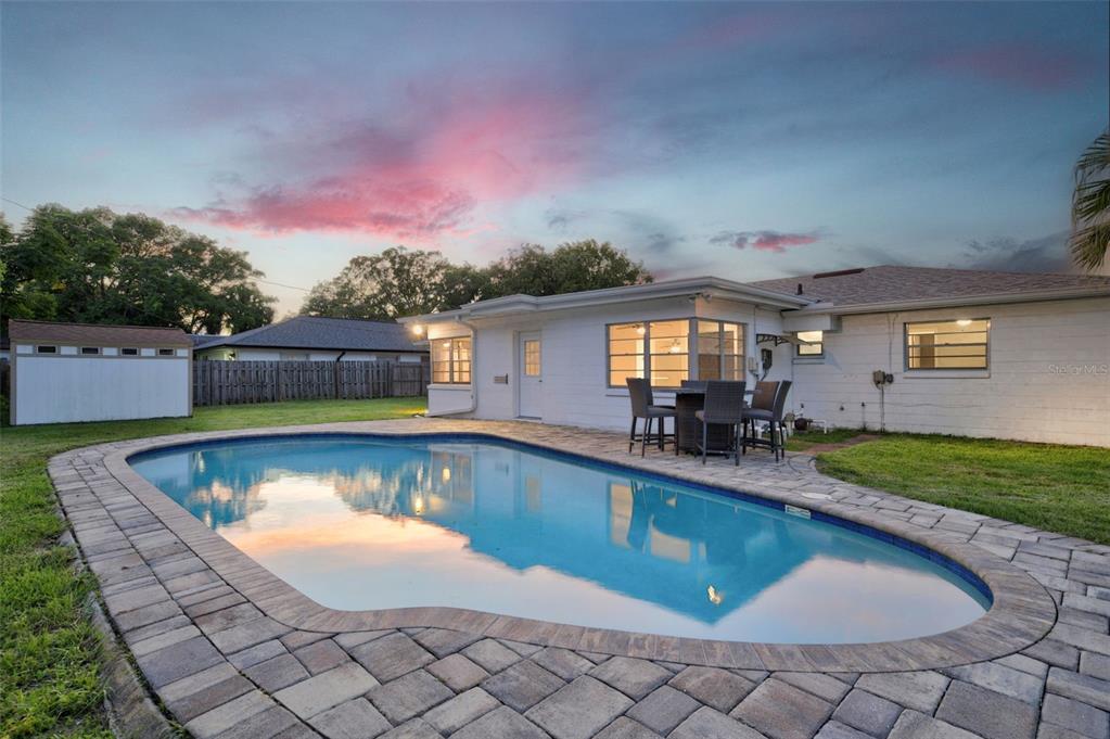 A backyard features a swimming pool with a paver deck and a white house exterior — 4854 RABAMA PLACE, ORLANDO, FL