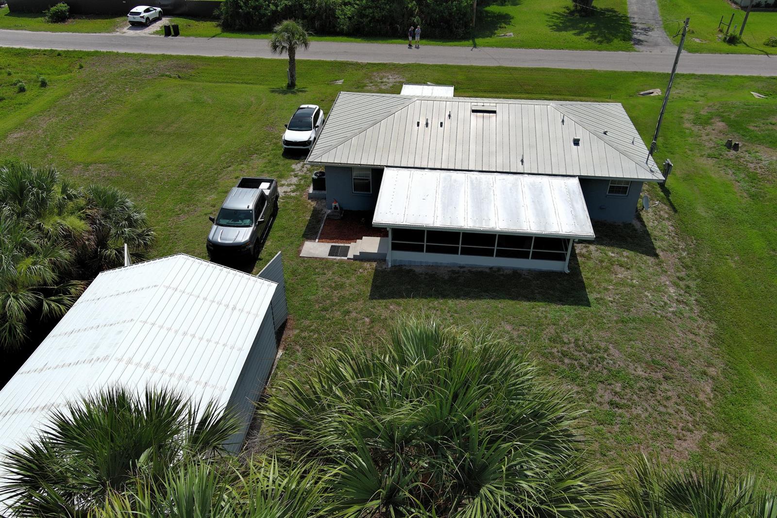 An aerial view shows a house with a metal roof, a screened porch, and two vehicles — 1163 Click Drive, Moore Haven FL 33471, MOORE HAVEN, FL