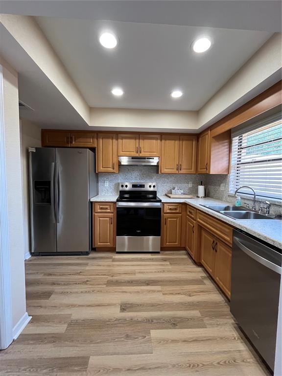 A kitchen featuring wood cabinets, stainless steel appliances, and light-colored wood-look flooring — 1052 MEDINAH DRIVE, WINTER HAVEN, FL