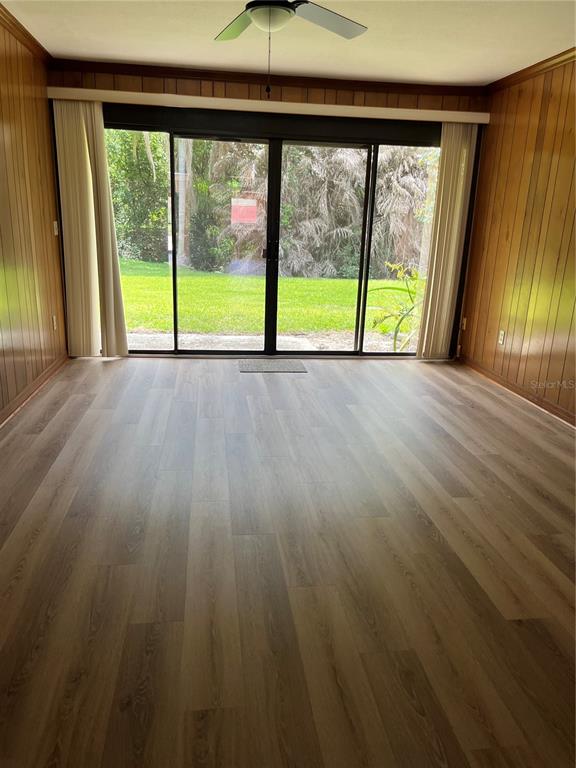 A room with wood-paneled walls, light wood-look flooring, and sliding glass doors leading outside — 1052 MEDINAH DRIVE, WINTER HAVEN, FL