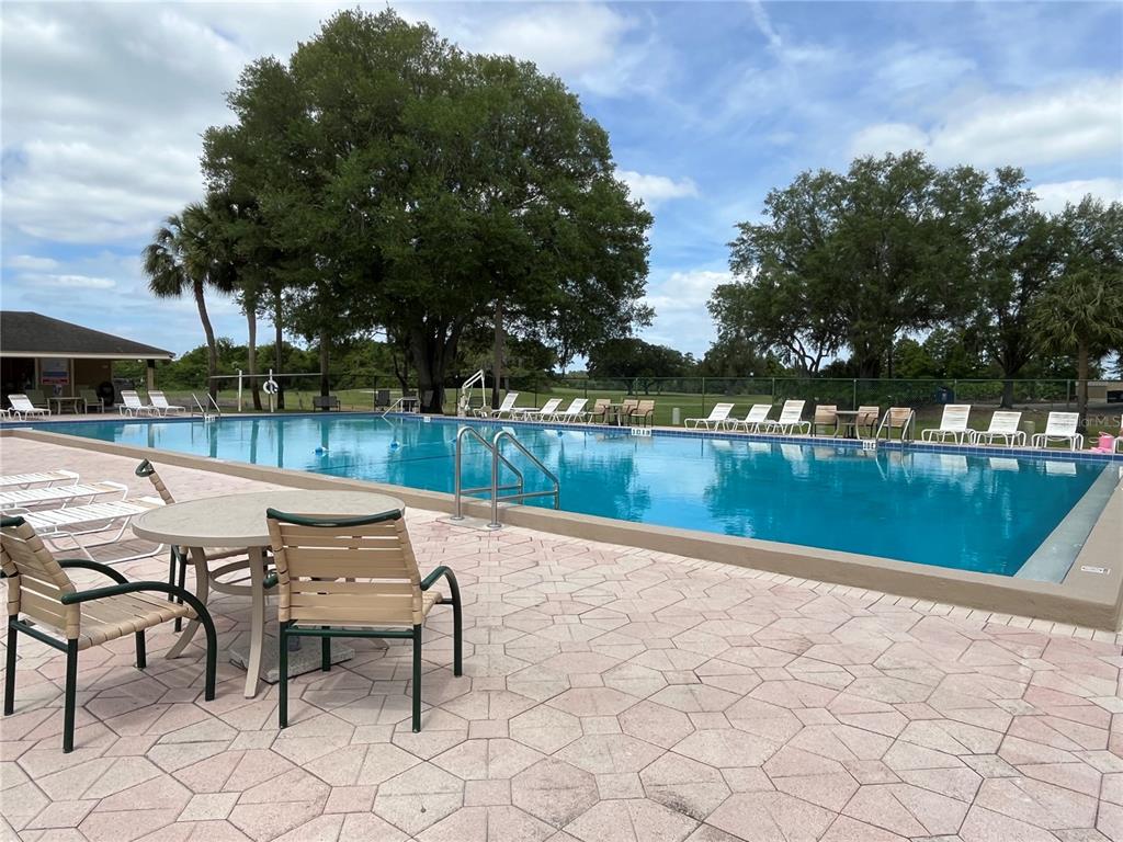 An outdoor swimming pool with lounge chairs and a patio table on a paved deck — 1052 MEDINAH DRIVE, WINTER HAVEN, FL