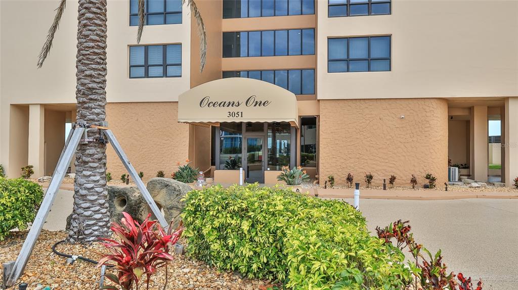 The exterior of a multi-story building features a tan facade, large windows, and a covered entrance — 3051 S ATLANTIC AVENUE UNIT 2206, DAYTONA BEACH, FL